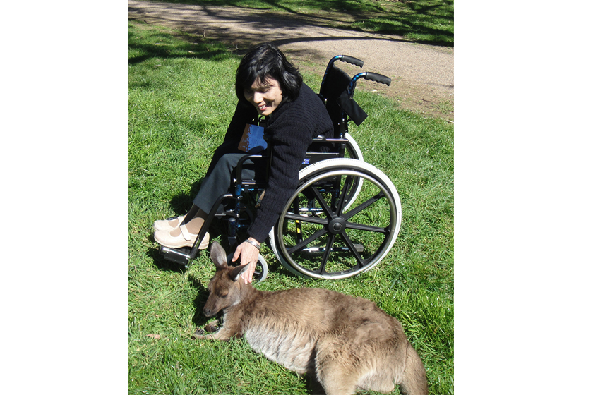 A disabled woman on a wheel chair is petting a kangaroo