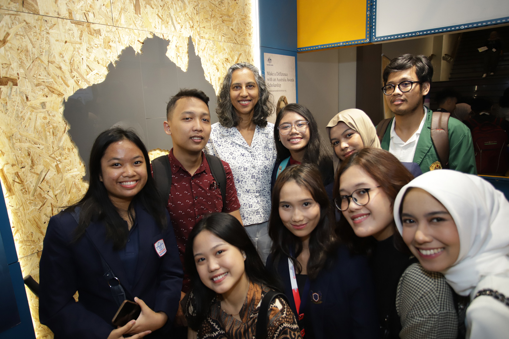 The Deputy Ambassador, Ms Gita Kamath, shares a joyful moment with university students from across Indonesia, capturing the vibrant energy of their visit to the booth.