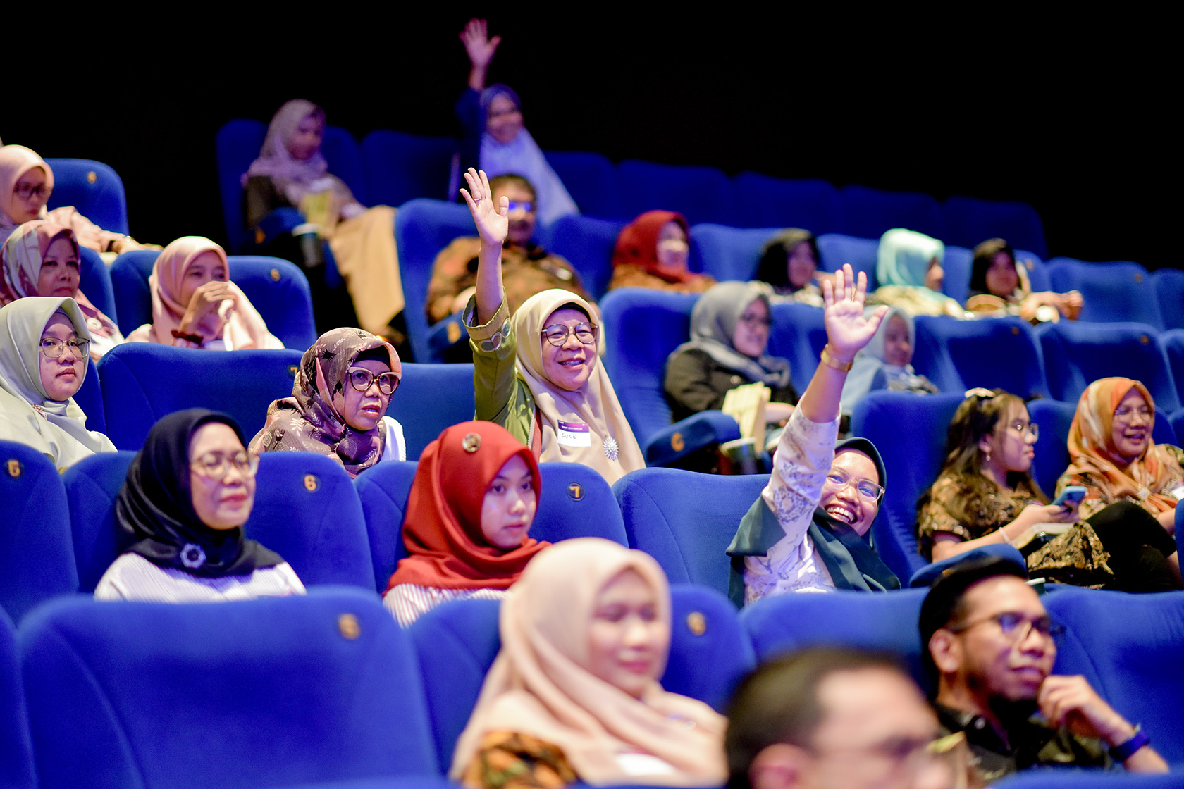 Participants of the 'Nobar' with OzAlum event in Padang raise their hands to participate in a lively and entertaining quiz.