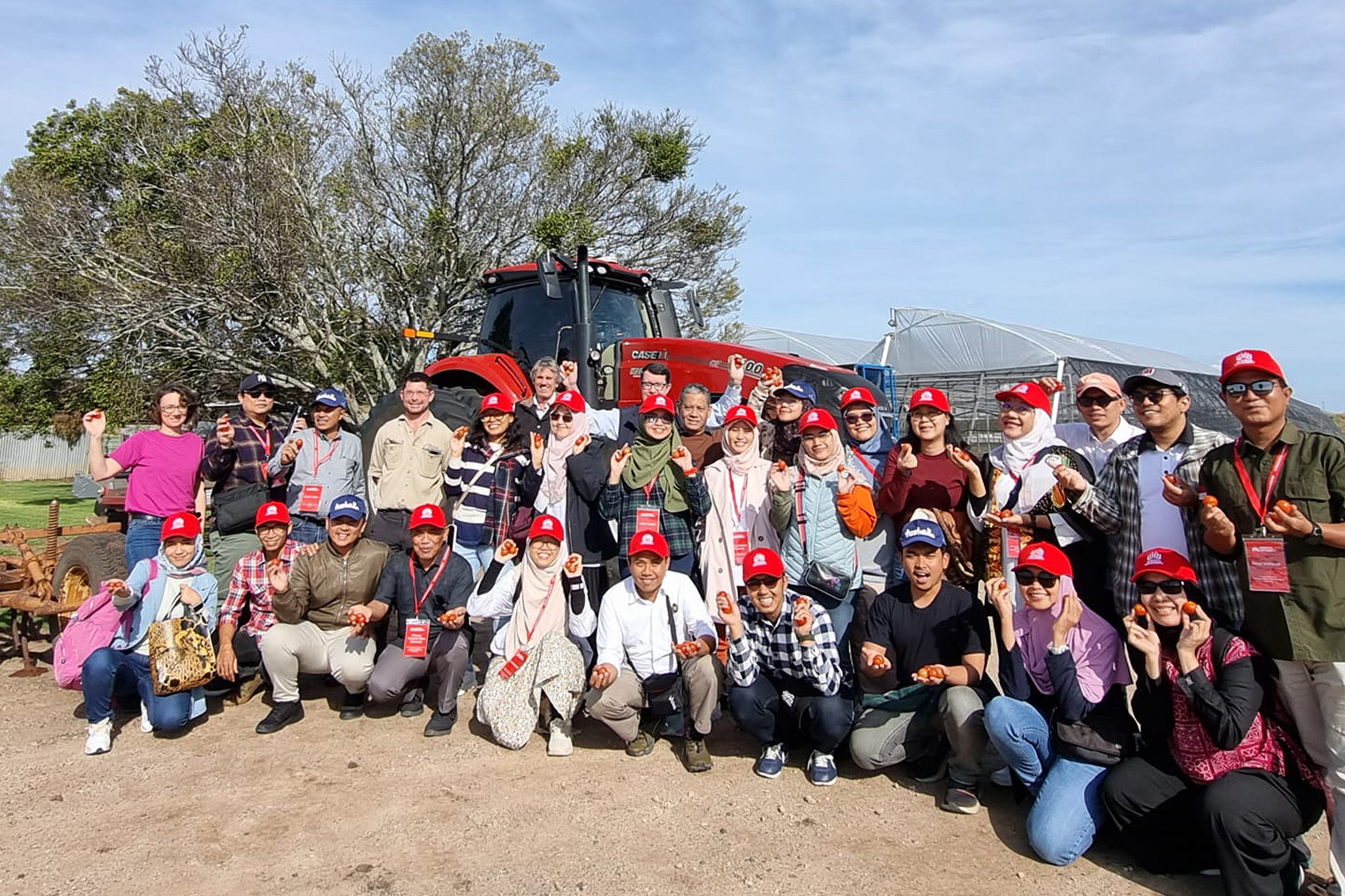 With a tractor in the background and fresh produce in hand, participants commemorate their farm visit with a photo