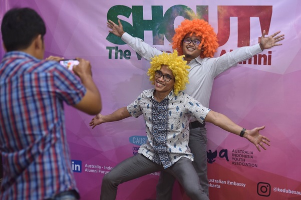 Two men are taken a photo wearing clown wigs