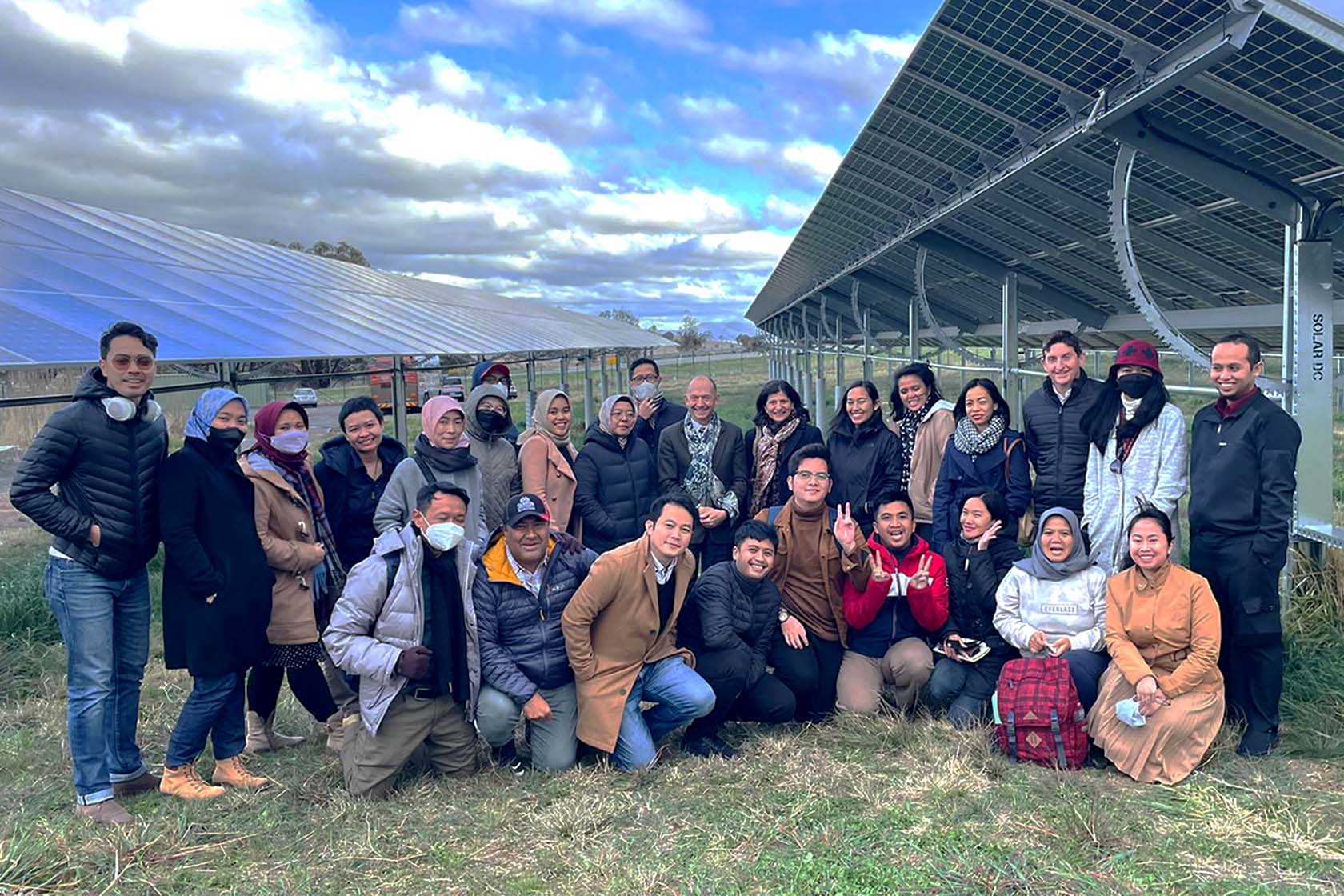 Participants take a photo outside on a solar panel farm