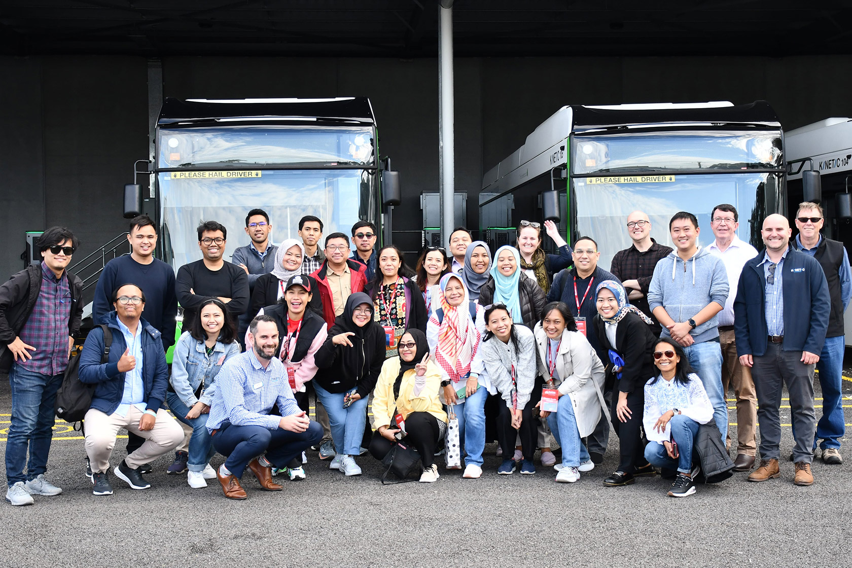 Participants of the Public Transport Management Short Course are smiling and posing in front of buses.